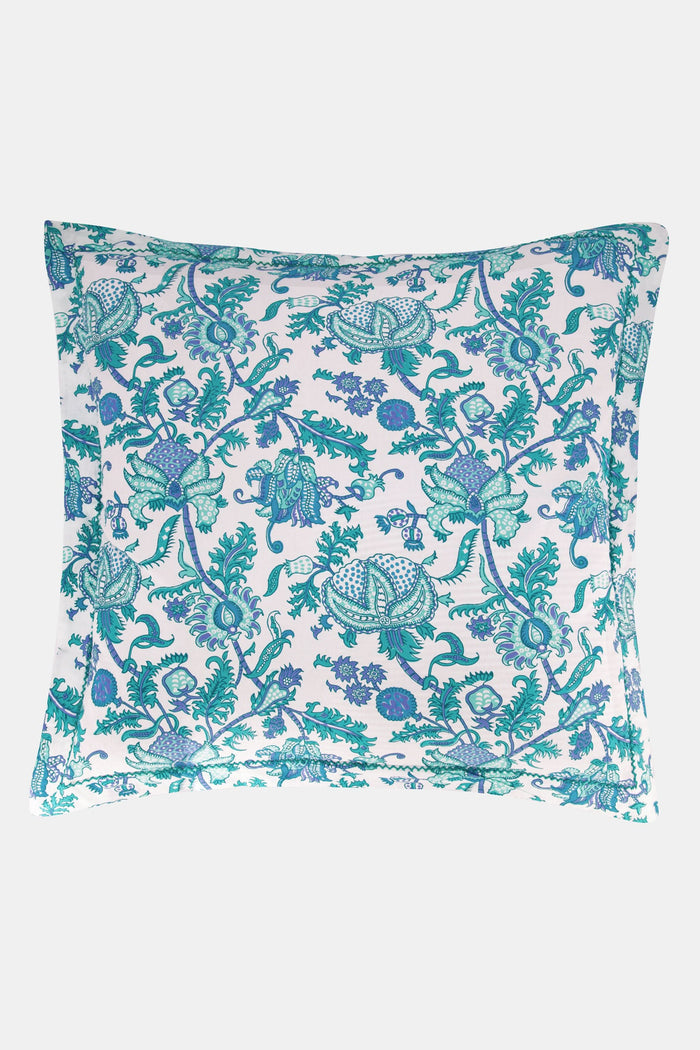 Two pillows with Amanda Pillowcase Set by Roller Rabbit rest on blue and turquoise floral bedding; the 100 cotton pillowcases coordinate with a white, leafy headboard and white curtains in the background.