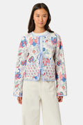 A woman stands facing forward against a plain white background, wearing the Roller Rabbit Amanda Sophie Jacket—a reversible cotton piece featuring blue, red, and pink floral and abstract designs—paired with cream-colored pants.
