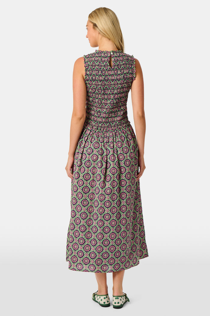 A woman wearing the Roller Rabbit Amelia Emma Dress, featuring a smocked bodice and maxi skirt, stands against a plain white background, paired with green polka-dot flats.
