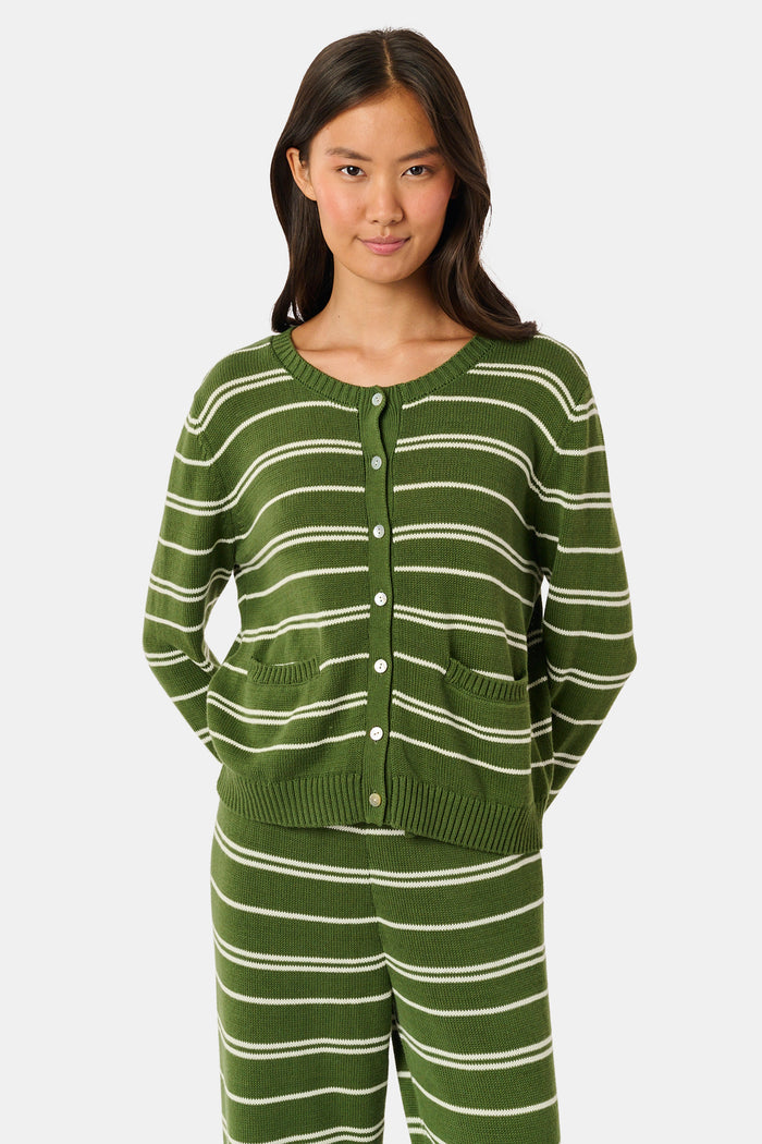 A woman stands facing forward, wearing the Roller Rabbit Autumn Stripe Laine Cardigan in olive green stripes with buttons and matching pants. She has long dark hair and a slight smile.
