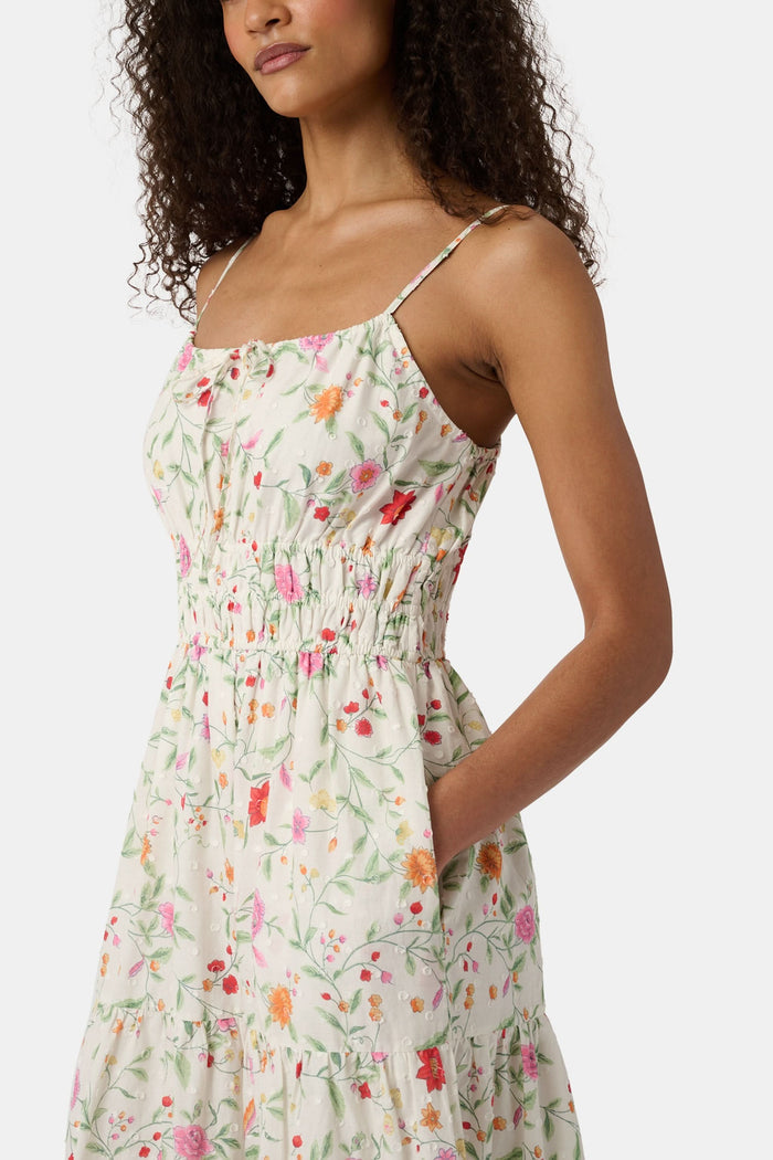 A woman with curly hair wears the Roller Rabbit Baroque Floral Karla Dress, a sleeveless ankle-length sundress with a smocked bodice, paired with beige espadrille flats against a plain light background.