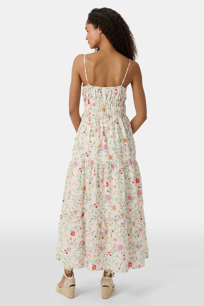 A woman with curly hair wears the Roller Rabbit Baroque Floral Karla Dress, a sleeveless ankle-length sundress with a smocked bodice, paired with beige espadrille flats against a plain light background.