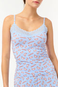A woman models the Roller Rabbit Breakfast In Bread Perry Cami, featuring scalloped lace trim and a playful croissant print. The photo is cropped from shoulders to hips against a plain white background.
