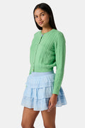 The Roller Rabbit Cable Stripe Moxie Cardigan is a bright forest green, long-sleeve cardigan featuring a cable-knit design. Crafted from soft cotton cashmere, it has a crew neckline and gold buttons down the front, shown against a plain white background.