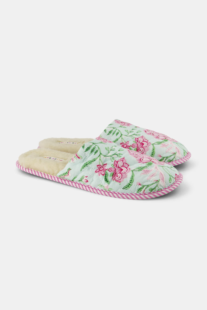 The Roller Rabbit Camellia Block Quilted Slippers are cozy, backless cotton slippers featuring a pink and green floral pattern on a light background, pink and white striped trim, and a soft cream-colored lining.
