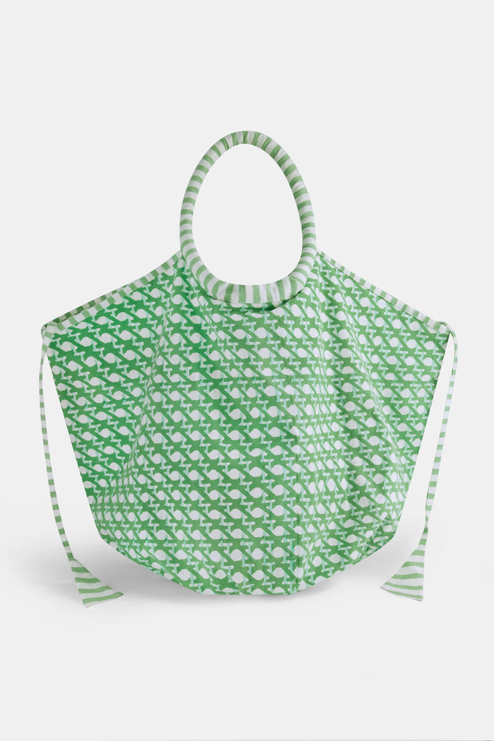 The Cane Bondi Bag by Roller Rabbit is a green and white tote with a wide, round handle, side ties, and a repeating fish pattern on soft cotton canvas. Its unique flared shape adds style to this charming everyday bag.