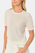 A woman wearing the Roller Rabbit Chain Pointelle Lauren Sweater in cream and white pants, standing against a white background.