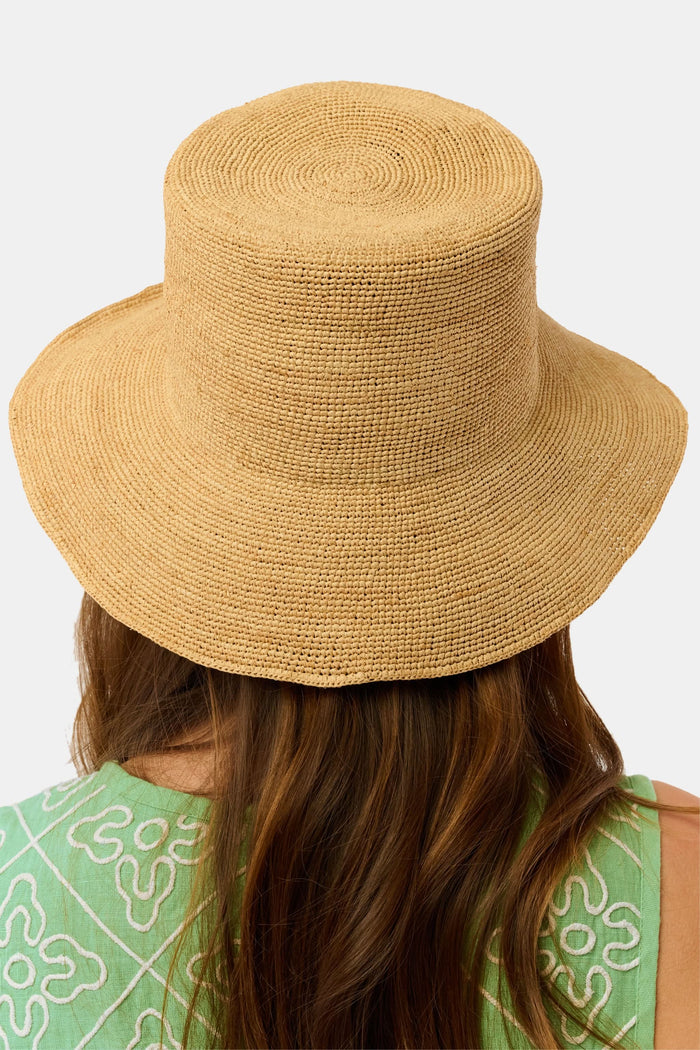 A person with long brown hair is seen from behind wearing the Hat Attack Chic Crochet Bucket Hat and a green top with white patterns against a plain background.