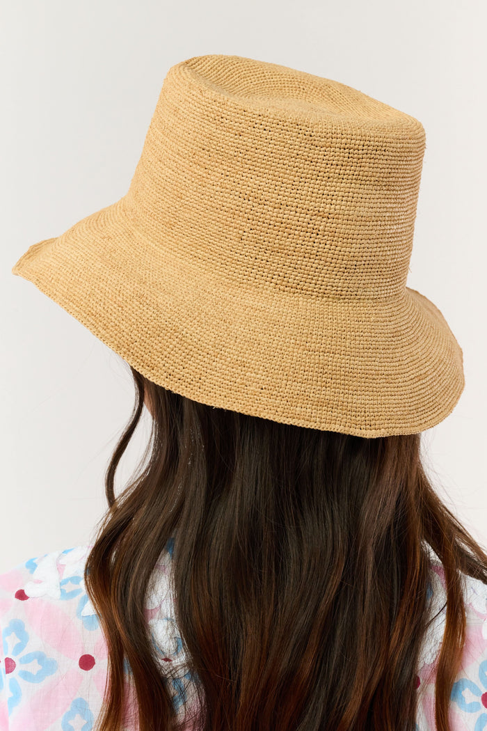 A person with long brown hair is seen from behind wearing the Hat Attack Chic Crochet Bucket Hat and a green top with white patterns against a plain background.