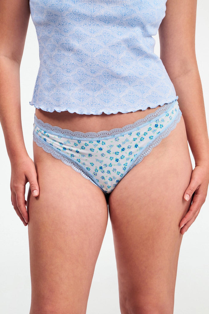 The Classic Core Bikini 4 Pack by Roller Rabbit includes four soft cotton modal panties, each with lace trim: green with hearts, light blue floral, white with blue paisley, and mint green with pink trim and embroidered hearts.