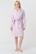 A person with long blonde hair stands barefoot against a plain white background, wearing the Roller Rabbit Disco Hearts Cosmo Robe with a belt tied at the waist.