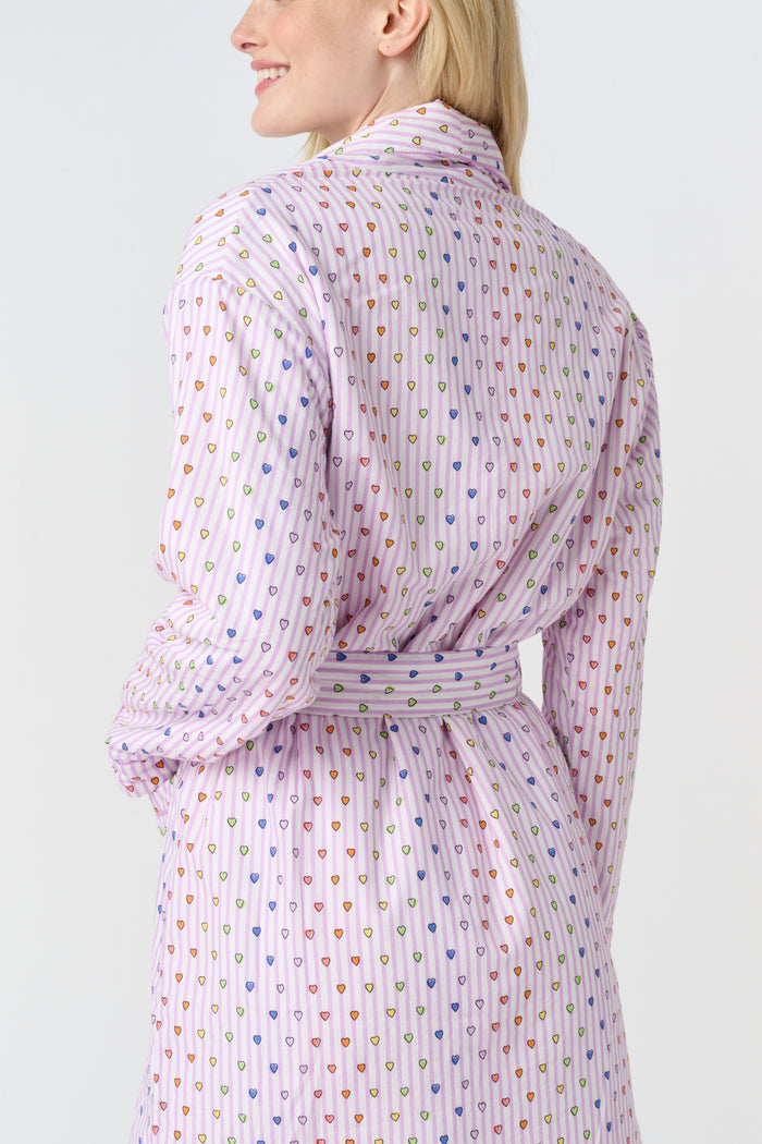A person with long blonde hair stands barefoot against a plain white background, wearing the Roller Rabbit Disco Hearts Cosmo Robe with a belt tied at the waist.