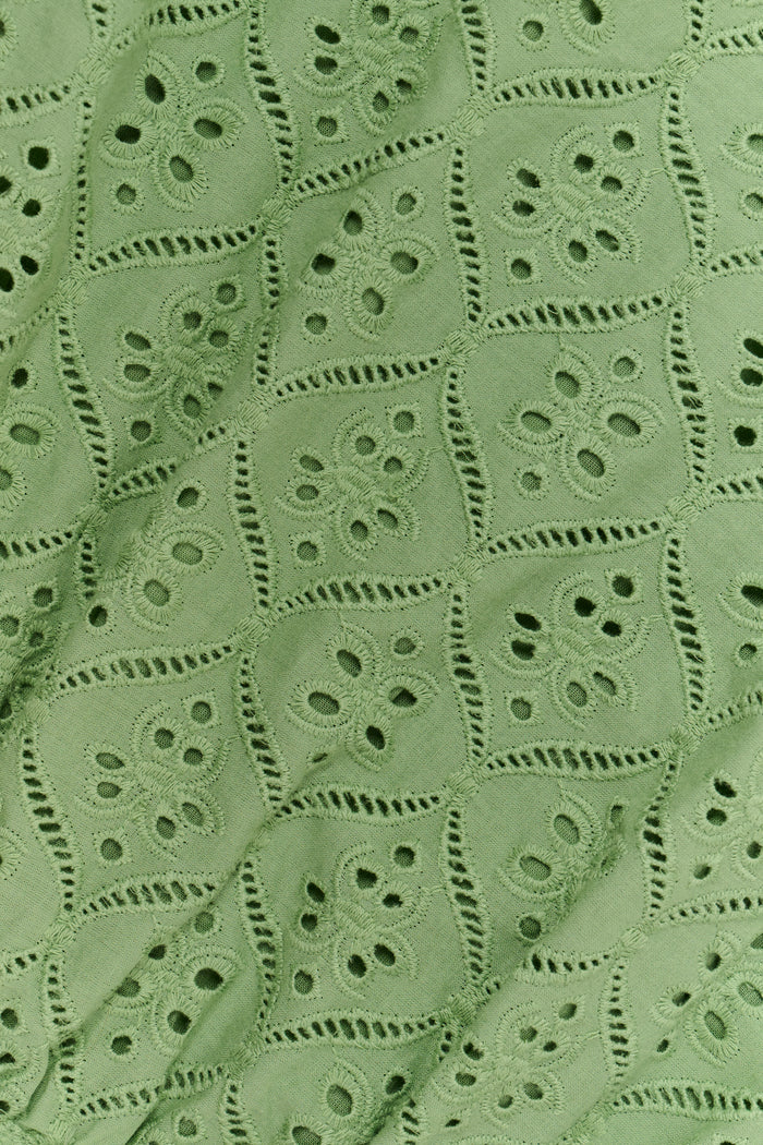 A woman wearing the Roller Rabbit Elsa Eyelet Nicole Top in sage green cotton, featuring an eyelet pattern and ruffled shoulder straps, shown from the shoulders to the waist against a plain background.