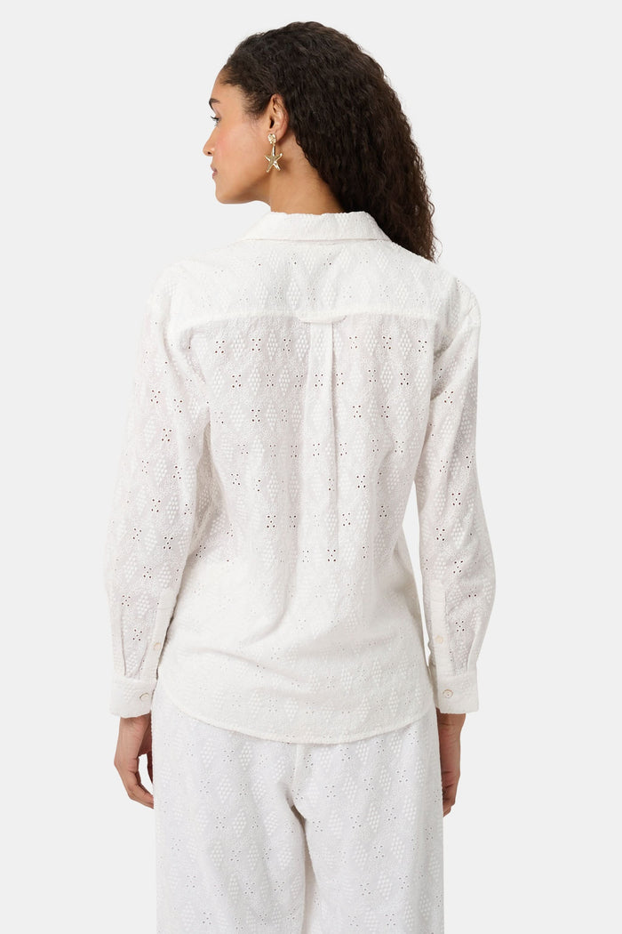 A woman with long curly hair wears the Roller Rabbit Eyelet Lattice Boyfriend Shirt in white, featuring a front pocket, paired with matching white pants against a plain background.