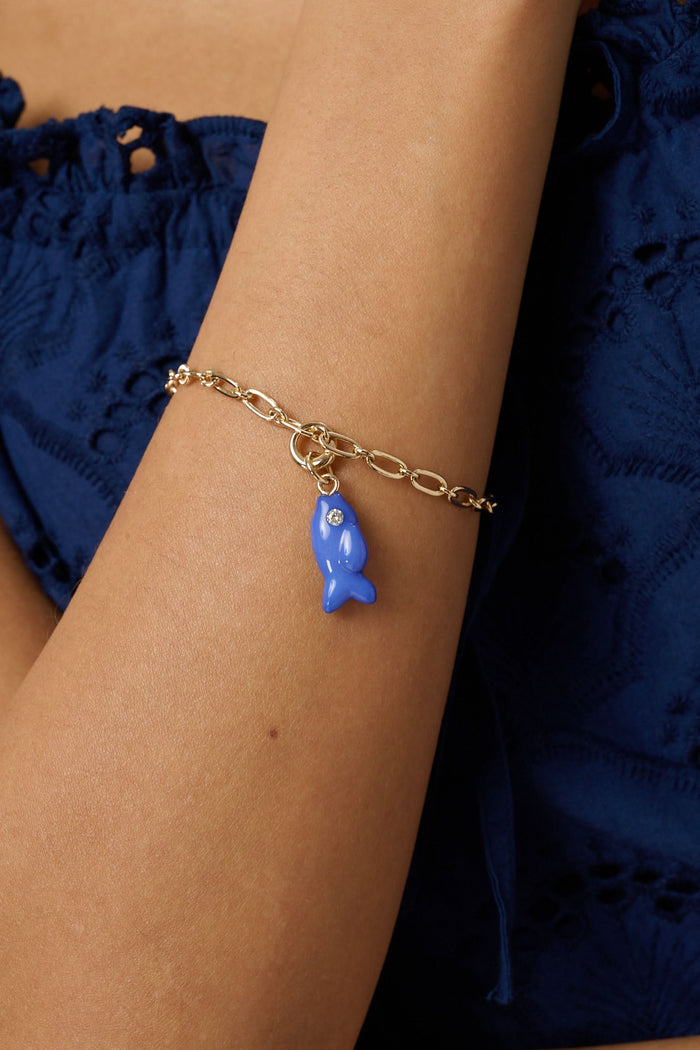 The Roller Rabbit Fish Charm features a small blue enamel fish with a sparkling stone eye, hanging from a gold-colored loop and bail, displayed on a plain light background.