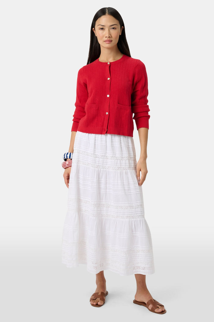 A person wears a red cardigan, the Florence Lace Carlisa Skirt by Roller Rabbit, brown slide sandals, and red, white, and blue bangle bracelets against a plain white background.