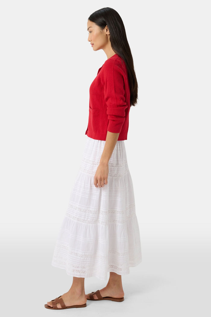 A person wears a red cardigan, the Florence Lace Carlisa Skirt by Roller Rabbit, brown slide sandals, and red, white, and blue bangle bracelets against a plain white background.