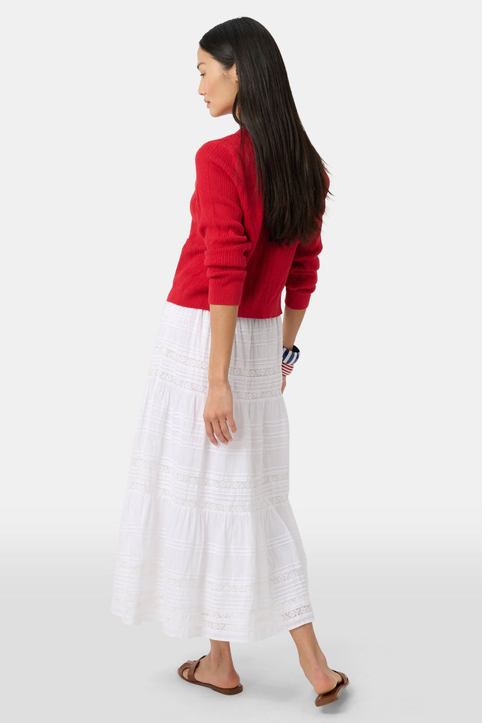 A person wears a red cardigan, the Florence Lace Carlisa Skirt by Roller Rabbit, brown slide sandals, and red, white, and blue bangle bracelets against a plain white background.