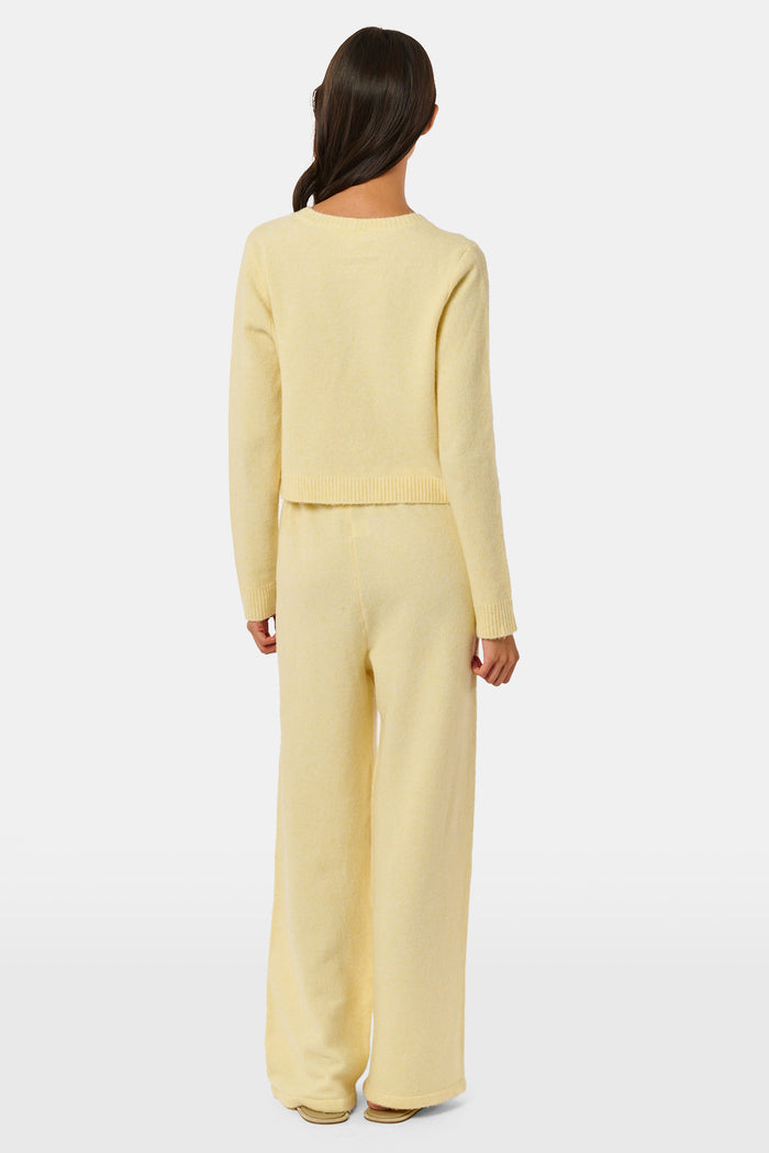 A person wearing the Roller Rabbit Gaia Pant paired with a light yellow knit sweater and beige slippers stands against a plain white background.