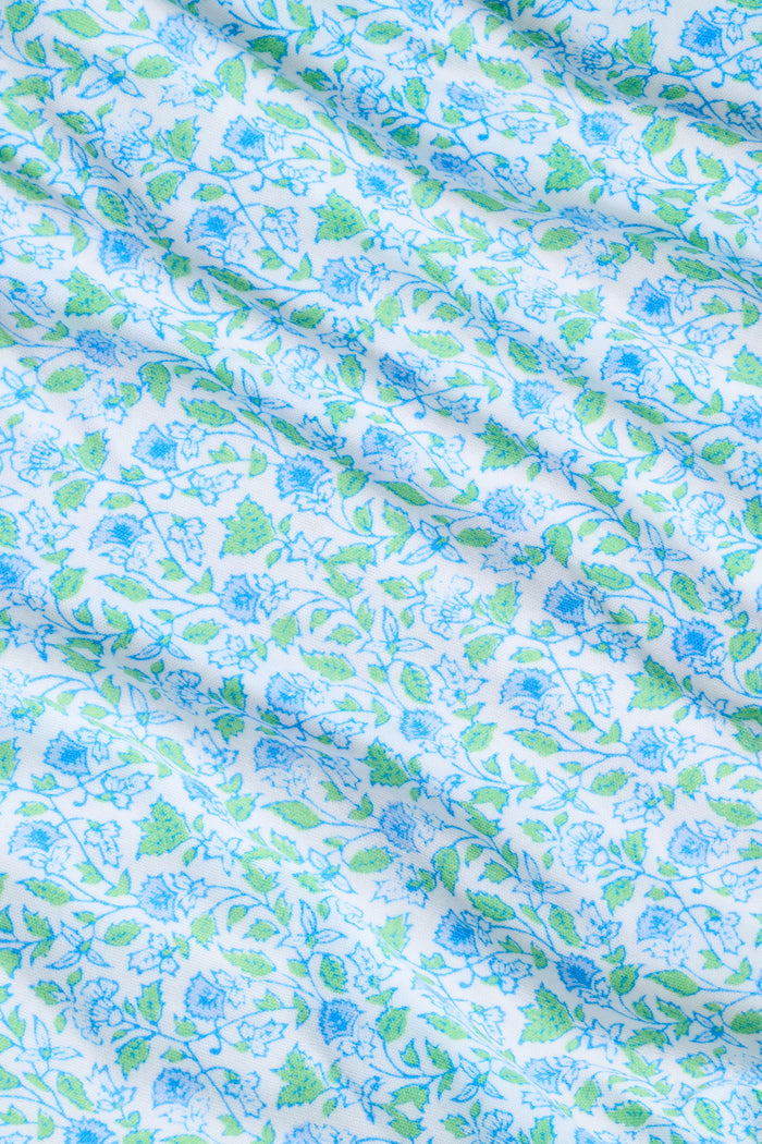 The Roller Rabbit Garden Gate Floral Daniela Slip Dress features a sleeveless, knee-length silhouette with thin straps, a blue and green floral Garden Gate print, and blue lace trim at the hem, shown against a plain white background.