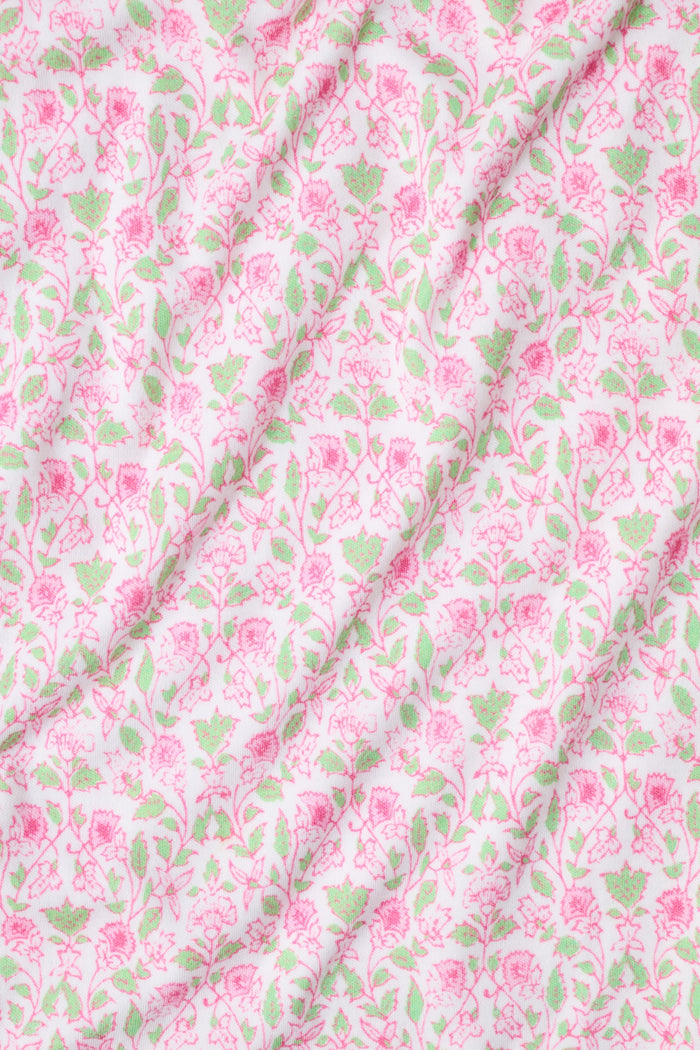 The Garden Gate Floral Lily Set by Roller Rabbit features a pink and white women's loungewear set with a sleeveless, V-neck camisole and loose pants. Made from soft Pima cotton, both pieces showcase a delicate floral pattern and light pink trim. The comfy tank and pants include a drawstring waist and ruffled hems for added comfort and style.