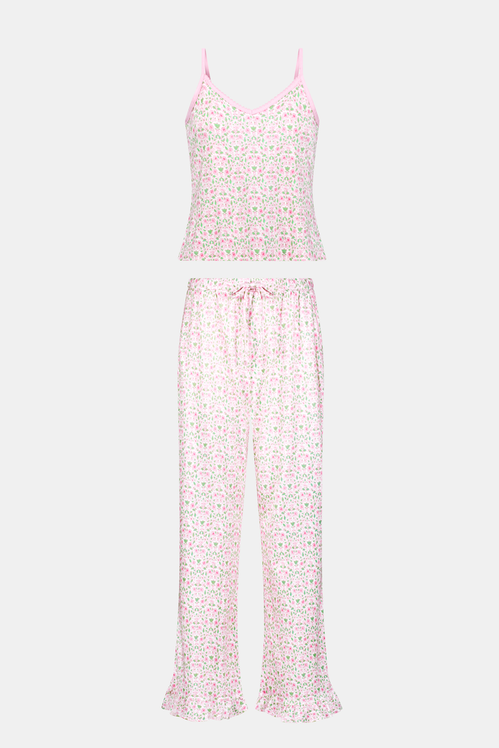 The Garden Gate Floral Lily Set by Roller Rabbit features a pink and white women's loungewear set with a sleeveless, V-neck camisole and loose pants. Made from soft Pima cotton, both pieces showcase a delicate floral pattern and light pink trim. The comfy tank and pants include a drawstring waist and ruffled hems for added comfort and style.