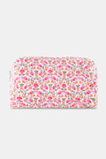 The Roller Rabbit Garden Gate Floral Quilted Makeup Bag is a rectangular, zippered bag crafted from 100 cotton and features a colorful floral print with pink, orange, and green flowers on a white background.