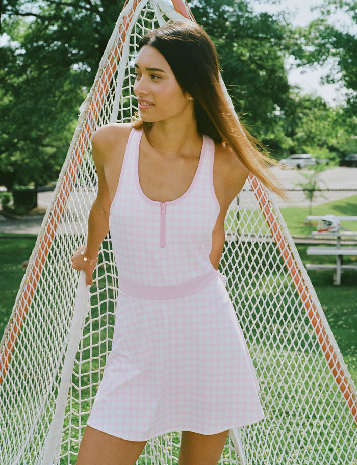 The Roller Rabbit Gingham Hearts Becky Active Dress is a sleeveless pink gingham dress featuring a fitted bodice, zipper front, and flared skirt, crafted from soft peached interlock fabric and shown on a plain white background.