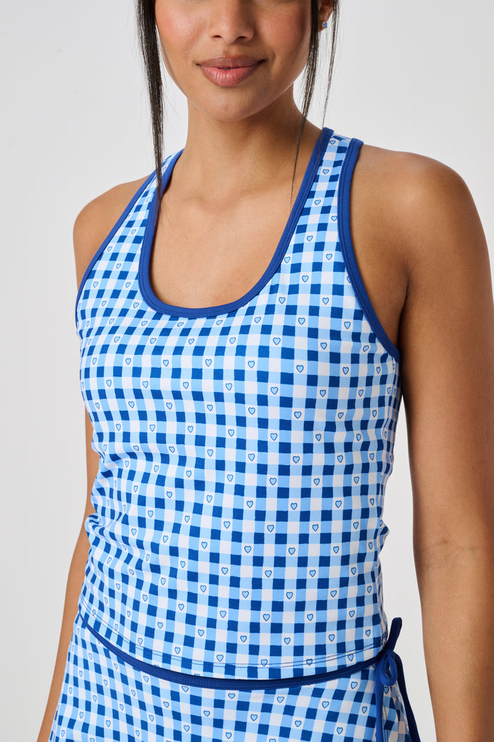A person wears the Roller Rabbit Gingham Hearts Bella Tank, a blue-and-white checkered racerback style with small heart details. The image is cropped at the shoulders and midsection, showing part of the matching skirt and the person’s head.