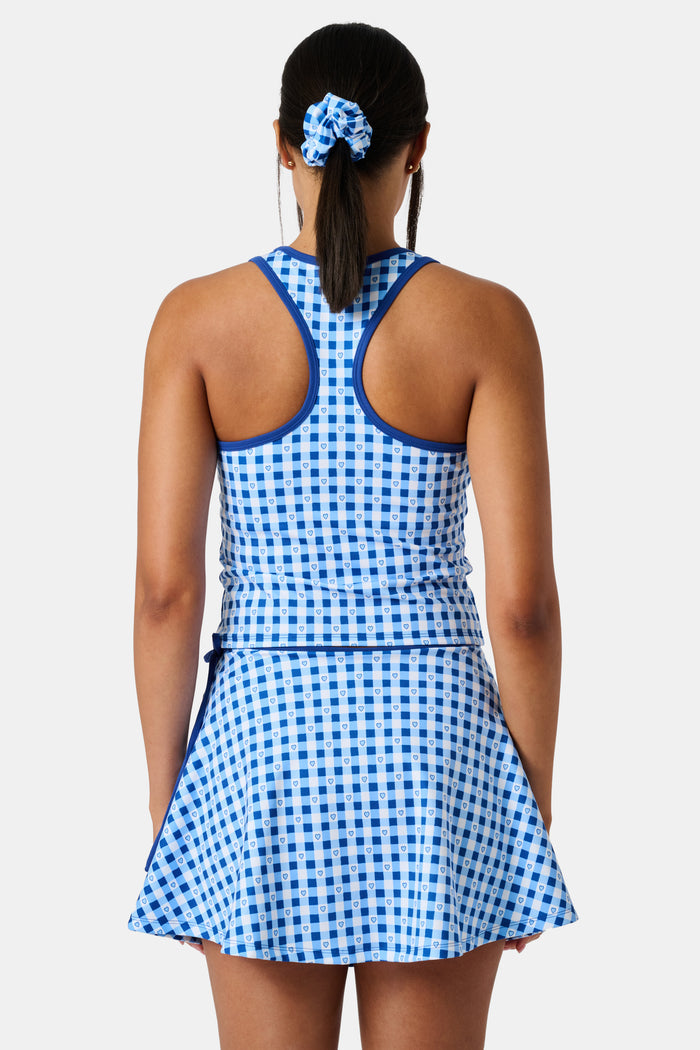 A person wears the Roller Rabbit Gingham Hearts Bella Tank, a blue-and-white checkered racerback style with small heart details. The image is cropped at the shoulders and midsection, showing part of the matching skirt and the person’s head.
