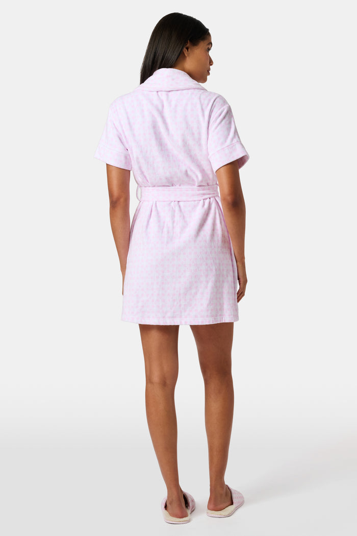 The Roller Rabbit Gingham Hearts Brooks Robe features a light pink gingham pattern with subtle hearts, crafted from soft cotton. This short-sleeve robe includes front pockets and a matching waist tie, and is displayed against a plain white background.