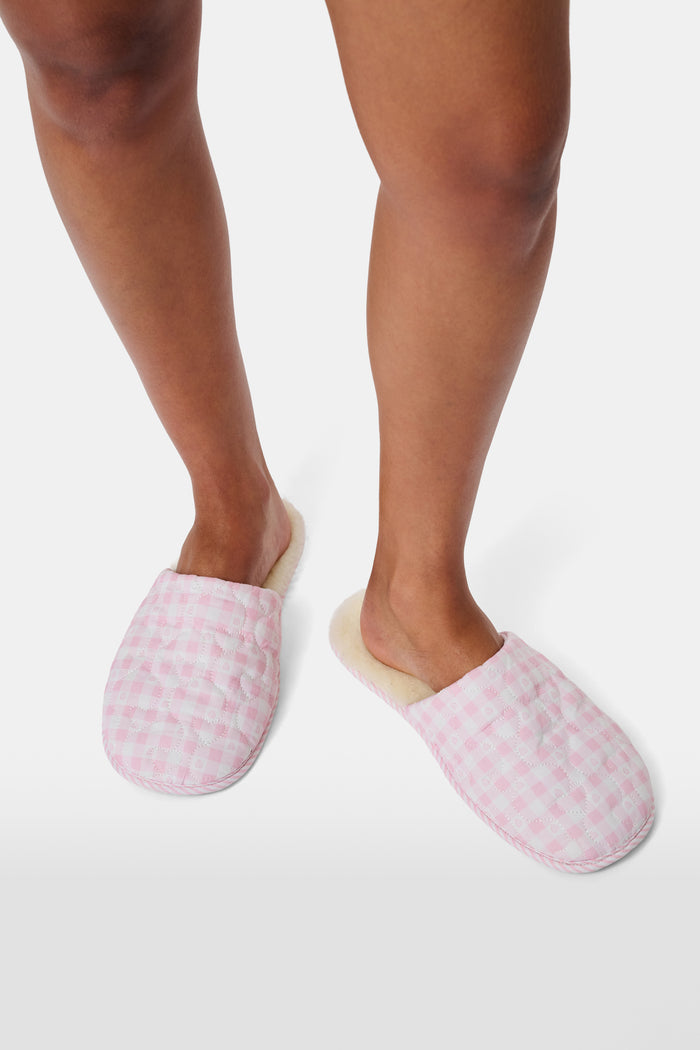 A pair of Roller Rabbit Gingham Hearts Quilted Slippers in pink and white, featuring closed toes and open heels, is displayed on a white background.