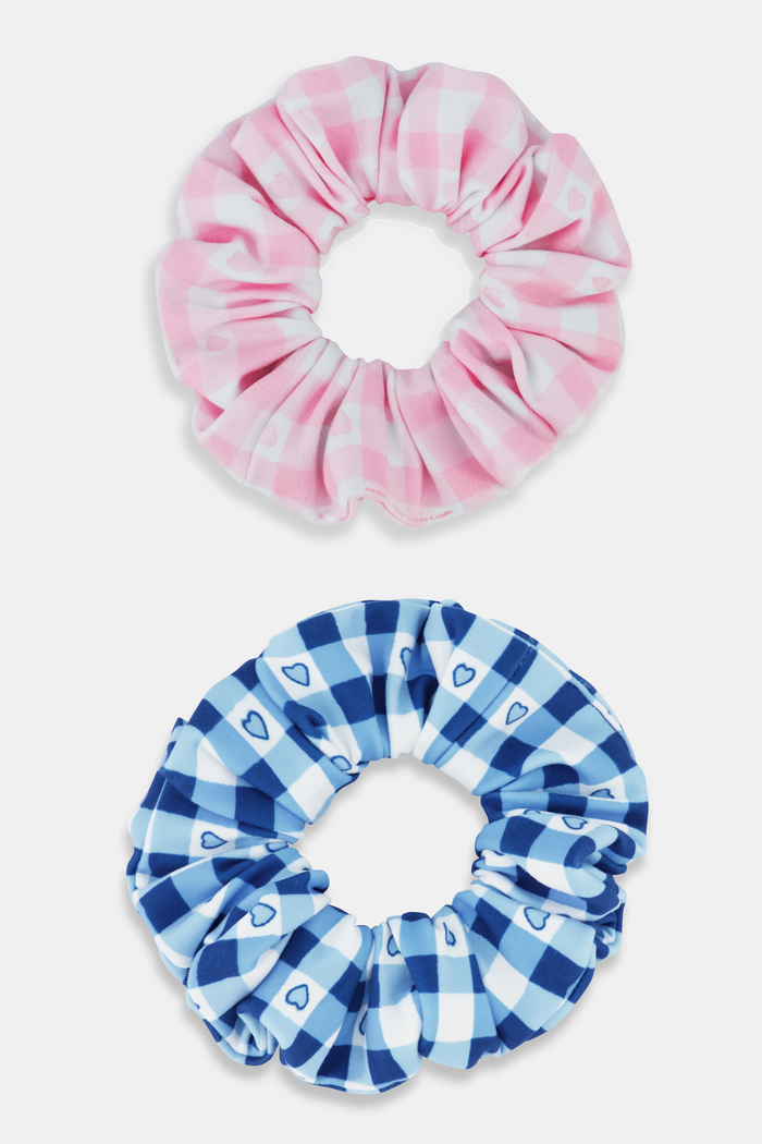The Roller Rabbit Gingham Hearts Scrunchie Set Of 2 features one pink and white gingham scrunchie with small hearts and one blue and white gingham scrunchie with small hearts, displayed vertically on a plain background.