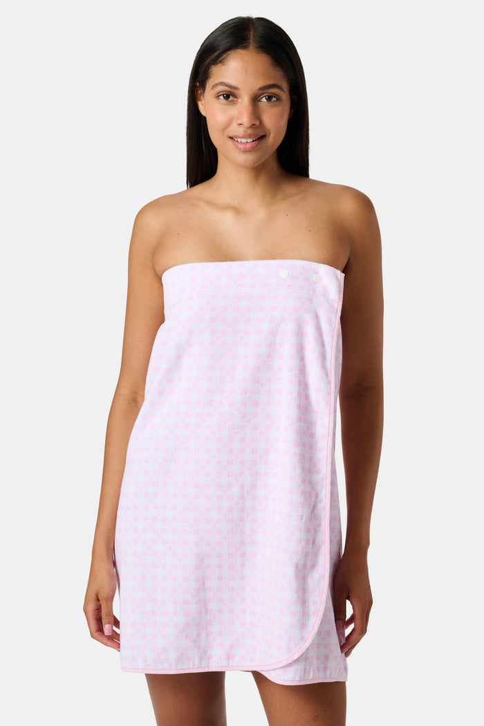 The Roller Rabbit Gingham Hearts Spa Headband is crafted from 100 cotton terrycloth and showcases a pink and white checkered pattern accented with small hearts. It features a convenient hook-and-loop fastener and is displayed laid flat on a white background.