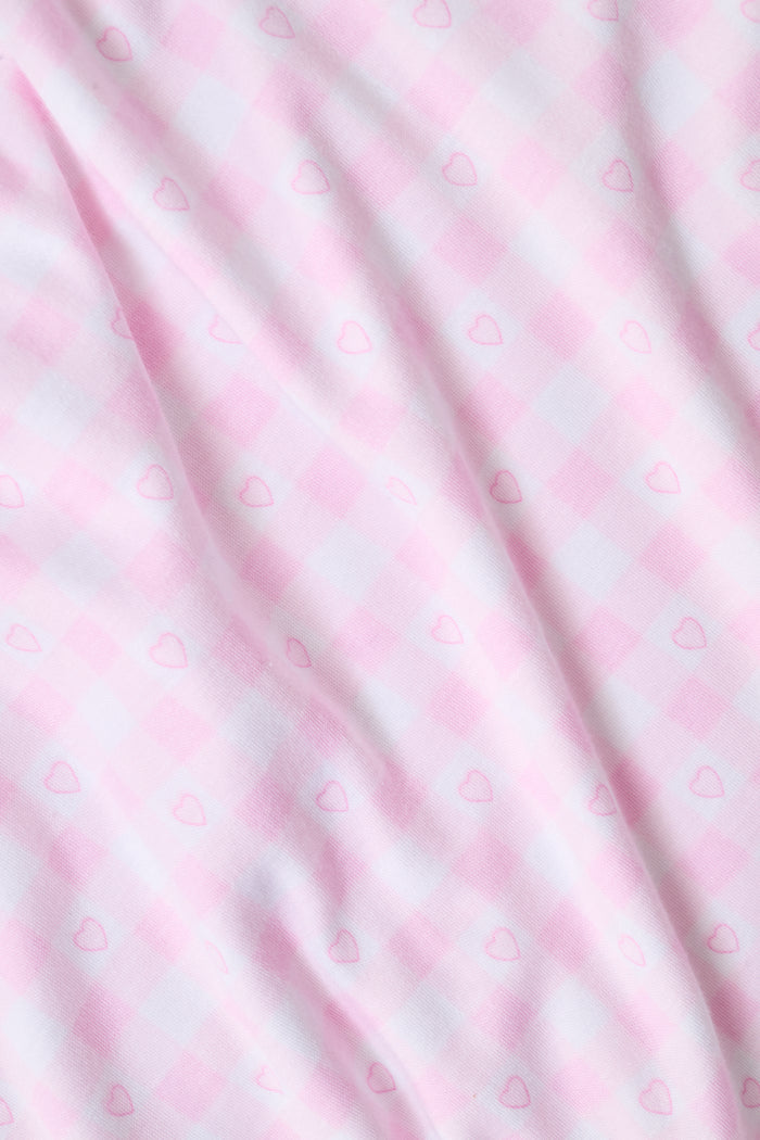The Gingham Hearts Wyatt Polo Pajamas by Roller Rabbit are a pink and white gingham short-sleeve pajama set, featuring a button-up shirt with chest pocket and matching shorts with a ruffled hem, all crafted from soft Pima cotton. This set is shown on a white background.