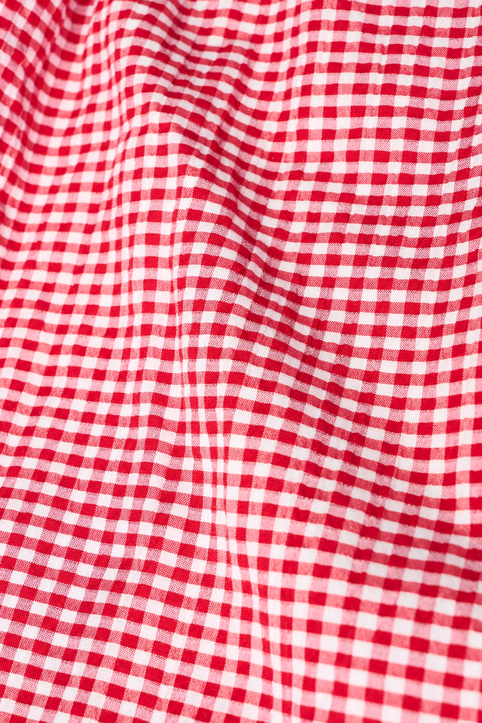 A woman wears the Roller Rabbit Gingham Quincy Top, a cotton blouse with puffed sleeves and red embroidery at the neckline. Only her upper body is visible.