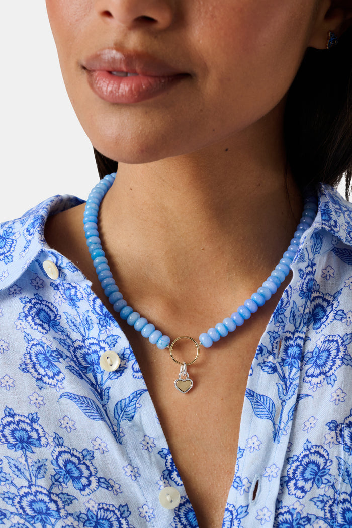 The Roller Rabbit Heart Charm is a heart-shaped pendant with a yellow gold center and a silver border, designed with a top loop for easy attachment to your favorite bracelet or necklace. It is displayed against a plain light gray background.