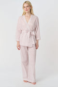 A person stands barefoot in the Roller Rabbit Hearts Christy Set—a light pink lounge set with small red hearts, featuring a belted wrap top and loose-fitting pants—against a plain white background.