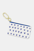 The Roller Rabbit Hearts Coin Pouch is a small, water-resistant white cotton canvas pouch adorned with a playful blue heart pattern. Featuring a gold keyring and zipper, this charming accessory is both stylish and practical.