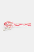 The Roller Rabbit Hearts Dog Leash features a pink, double-sided design with small red heart patterns and a silver clasp, displayed coiled on a white background.