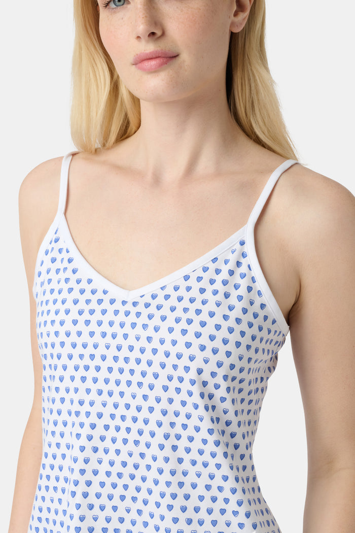 A woman wears the Roller Rabbit Hearts Mischa Set, a Pima cotton loungewear set with a white base and blue hearts. The set includes a sleeveless camisole top and shorts, styled against a plain light background.