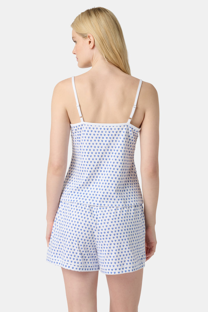 A woman wears the Roller Rabbit Hearts Mischa Set, a Pima cotton loungewear set with a white base and blue hearts. The set includes a sleeveless camisole top and shorts, styled against a plain light background.
