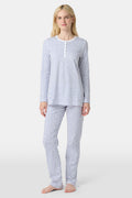 A person with light skin and long blonde hair stands barefoot in Roller Rabbit’s Hearts Pajamas—a matching set made from soft Pima cotton, featuring a white background with small blue and red heart patterns.