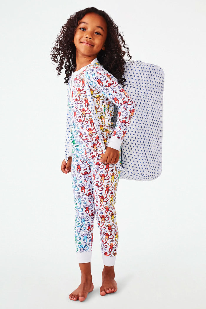 The Roller Rabbit Hearts Sleepover Bag is a large white bag with small blue hearts, a drawstring top, an external zippered pocket with two blue exclamation points, and "sleepover" printed below. Ideal for carrying kids' sleeping bags.