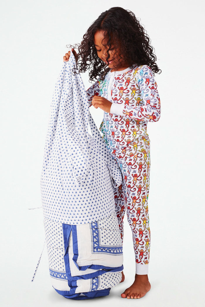 The Roller Rabbit Hearts Sleepover Bag is a large white bag with small blue hearts, a drawstring top, an external zippered pocket with two blue exclamation points, and "sleepover" printed below. Ideal for carrying kids' sleeping bags.