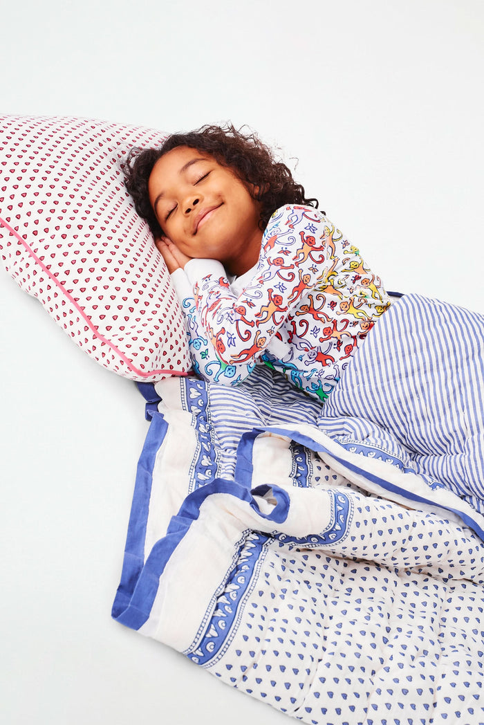 The Roller Rabbit Hearts Sleepover Bag is a large white bag with small blue hearts, a drawstring top, an external zippered pocket with two blue exclamation points, and "sleepover" printed below. Ideal for carrying kids' sleeping bags.