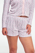 A person wears the Roller Rabbit Hearts Vine Brooklyn Boxer—matching long-sleeve, button-up pajama top and shorts with a pink, green, and white floral stripe pattern—standing against a white background.