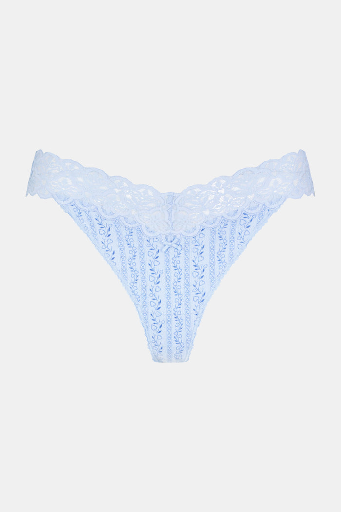 A person models the Roller Rabbit Hearts Vine Jay Thong in light blue lace with floral and stripe patterns, paired with a matching camisole top, shown from shoulders to hips against a plain background.