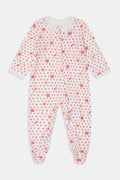 A woman in the Roller Rabbit Autumn Hearts Fiora Pajamas and brown boots sits on a wooden fence, smiling and resting one arm on a tree branch in a sunny outdoor setting, evoking the coziness of fall sleepwear.
