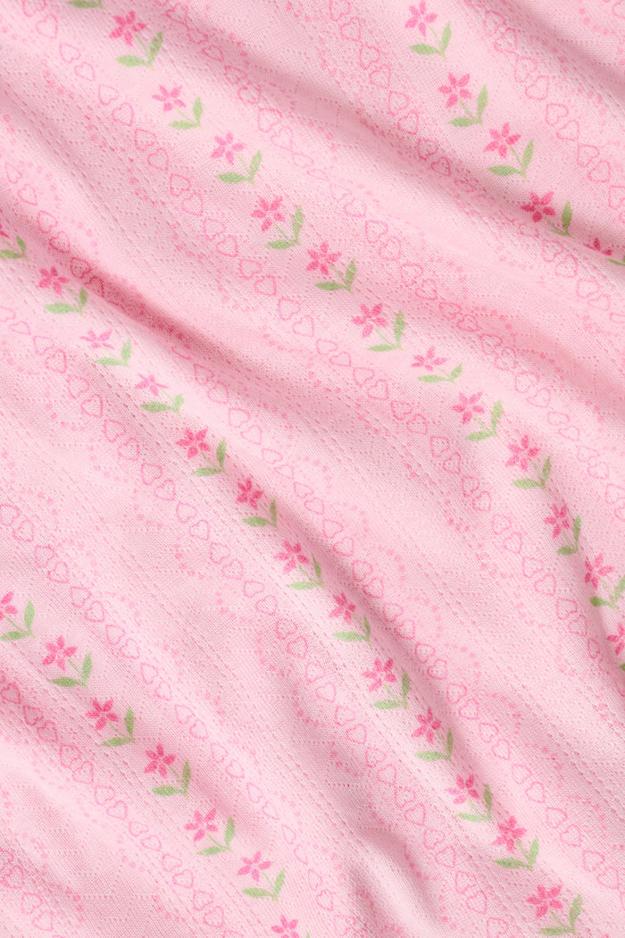 The Kids Daisy Heart Stripe Lucy Pants by Roller Rabbit are crafted from soft Pima cotton genie pant fabric in rose pink, featuring an elastic waistband and cuffs, with a subtle striped pattern and small floral designs throughout—making them a charming addition to girls' fashion.